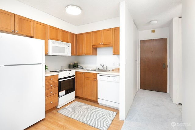 kitchen featuring sink, white appliances, and light wood-type flooring