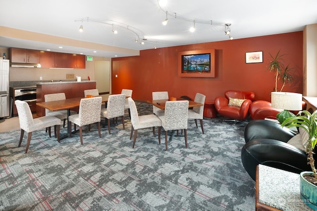 carpeted dining room with track lighting