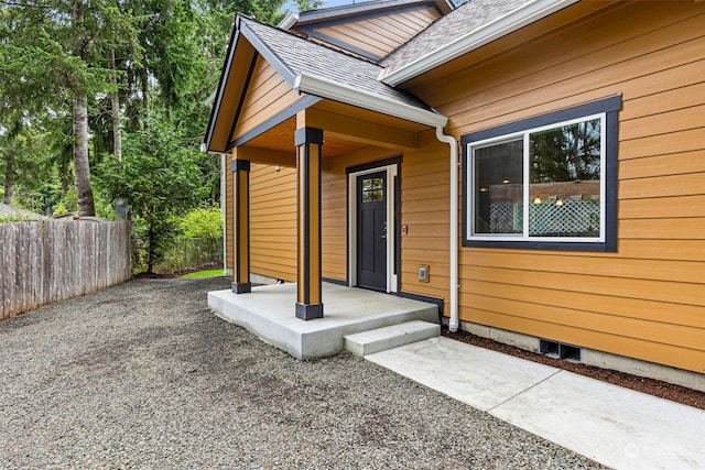 property entrance featuring roof with shingles and fence