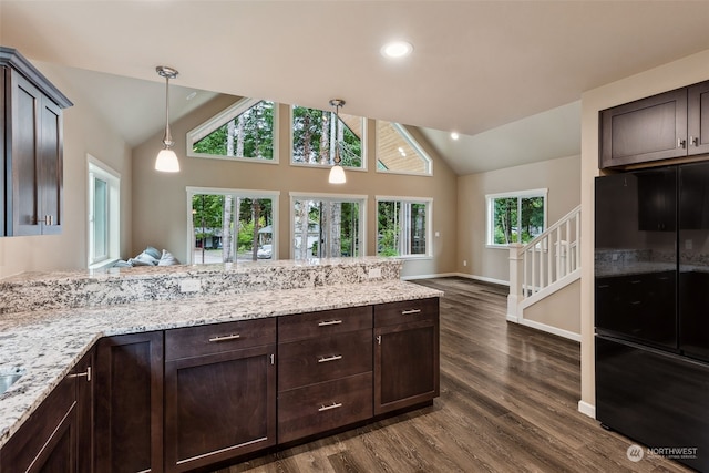kitchen with light stone counters, vaulted ceiling, pendant lighting, dark brown cabinetry, and dark wood-style flooring