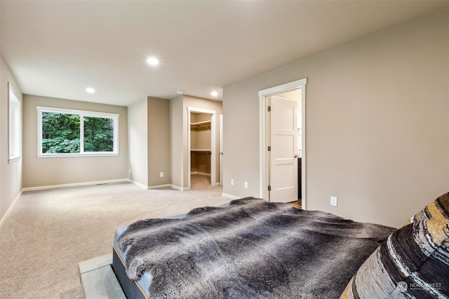 carpeted bedroom featuring baseboards, recessed lighting, and a walk in closet