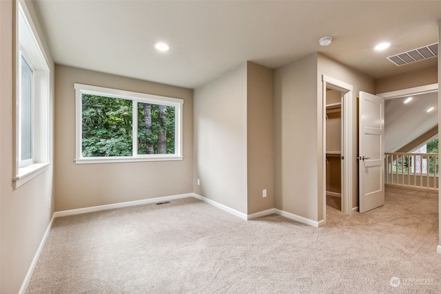 unfurnished bedroom featuring a walk in closet, carpet floors, visible vents, and baseboards