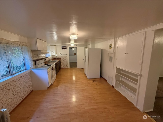 kitchen with white cabinetry, white appliances, sink, and light hardwood / wood-style flooring