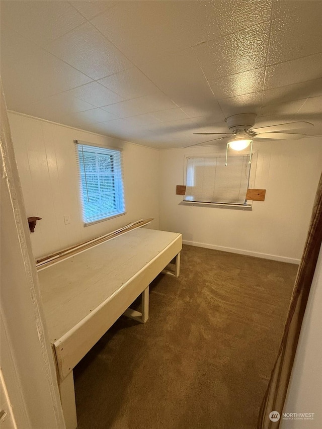 unfurnished bedroom featuring dark colored carpet and ceiling fan