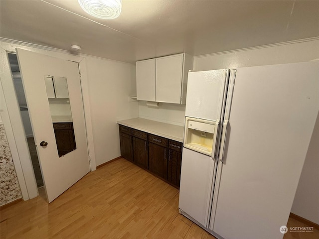 kitchen featuring dark brown cabinets, white refrigerator with ice dispenser, white cabinets, and light wood-type flooring