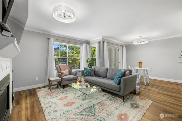 living room with a brick fireplace, dark hardwood / wood-style flooring, and ornamental molding