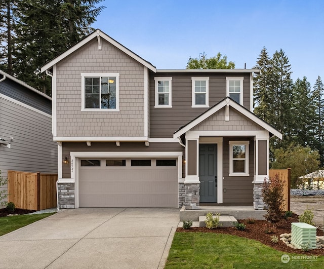 craftsman house featuring stone siding, driveway, an attached garage, and fence