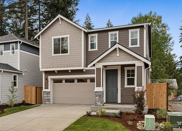 craftsman-style home with stone siding, concrete driveway, fence, and a garage