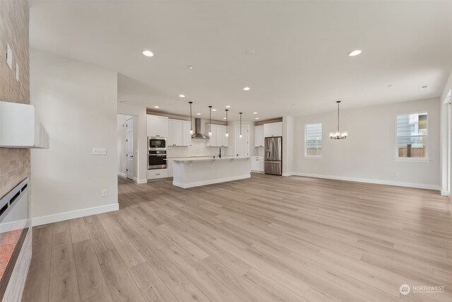 unfurnished living room featuring a fireplace, recessed lighting, an inviting chandelier, light wood-type flooring, and baseboards