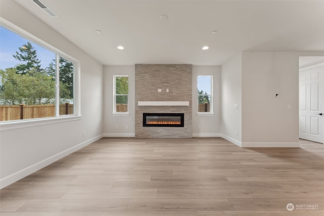 unfurnished living room with light wood finished floors, a fireplace, baseboards, and recessed lighting