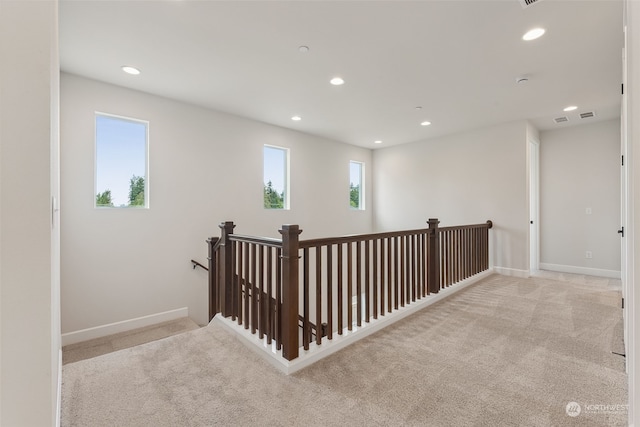 hallway featuring recessed lighting, baseboards, light carpet, and an upstairs landing