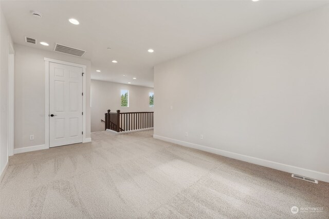 empty room featuring light colored carpet, visible vents, baseboards, and recessed lighting