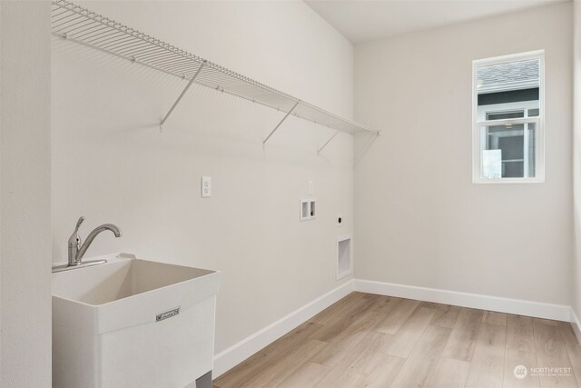 laundry area featuring hookup for a washing machine, laundry area, a sink, light wood-style floors, and electric dryer hookup