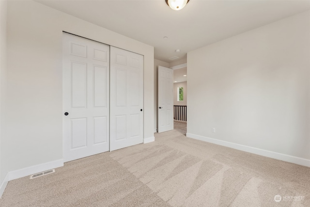 unfurnished bedroom with light carpet, baseboards, visible vents, and a closet