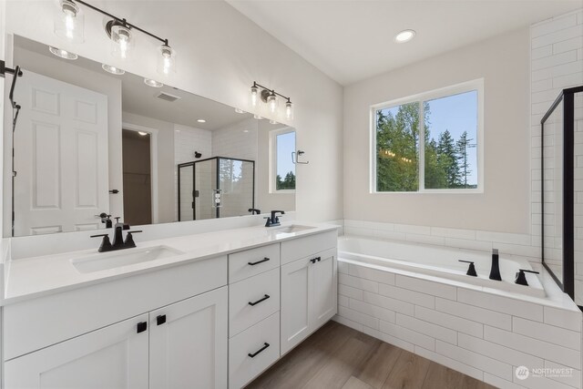 full bath featuring a garden tub, wood finished floors, a sink, and a shower stall