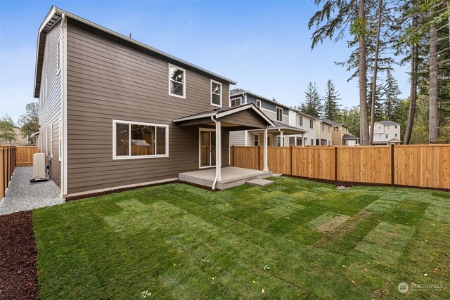 back of house featuring central AC, a lawn, a patio area, and a fenced backyard