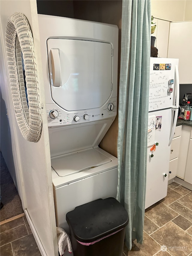 washroom with stacked washer / dryer and dark tile patterned floors