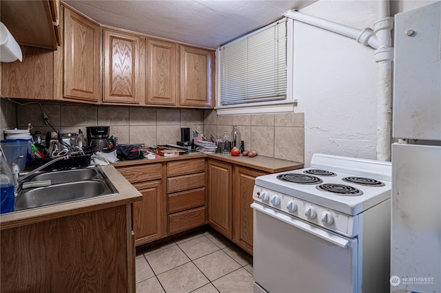 kitchen featuring sink, white appliances, light tile patterned floors, and tasteful backsplash