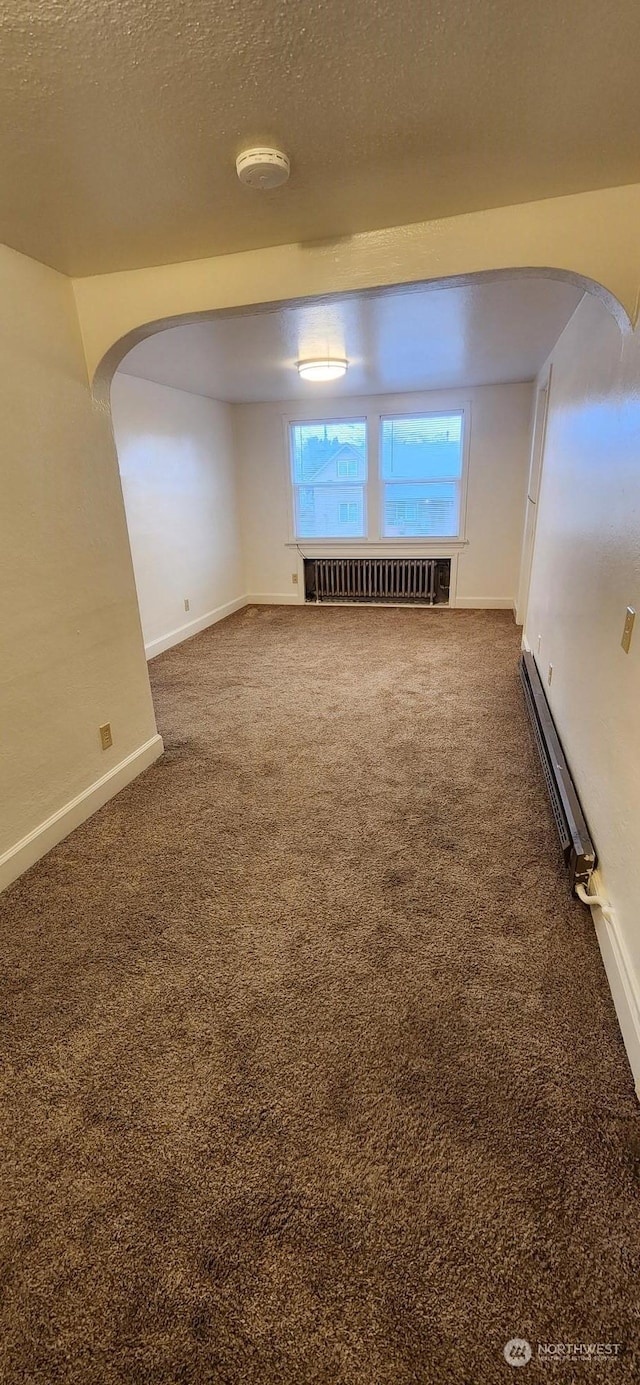 spare room featuring radiator, a baseboard heating unit, carpet floors, and a textured ceiling