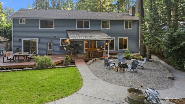 rear view of property featuring a fire pit, a yard, and a wooden deck