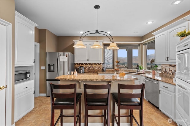 kitchen with stainless steel appliances, sink, a kitchen island, and white cabinets