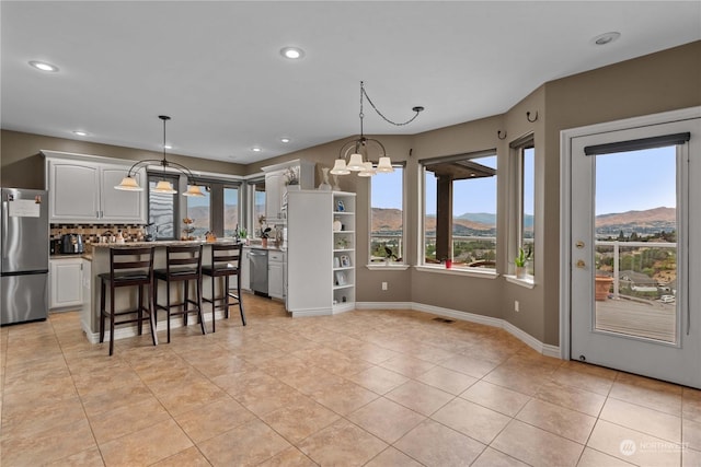 kitchen with decorative light fixtures, a breakfast bar area, stainless steel appliances, a mountain view, and an inviting chandelier