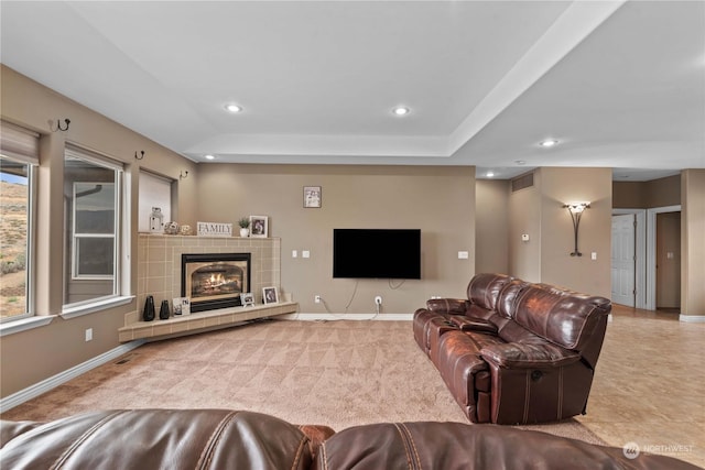 carpeted living room with a raised ceiling and a tile fireplace