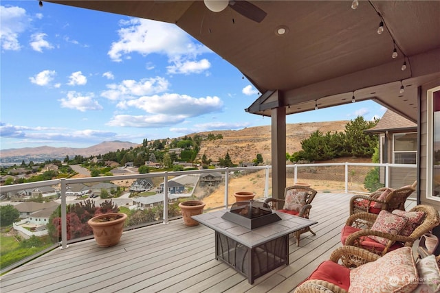 wooden deck featuring ceiling fan, an outdoor fire pit, and a mountain view