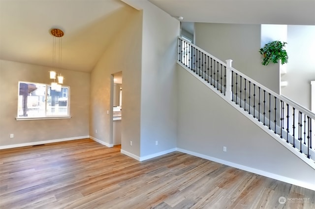 interior space featuring high vaulted ceiling, hardwood / wood-style floors, and a chandelier