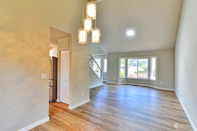 empty room featuring lofted ceiling, light hardwood / wood-style floors, and a chandelier