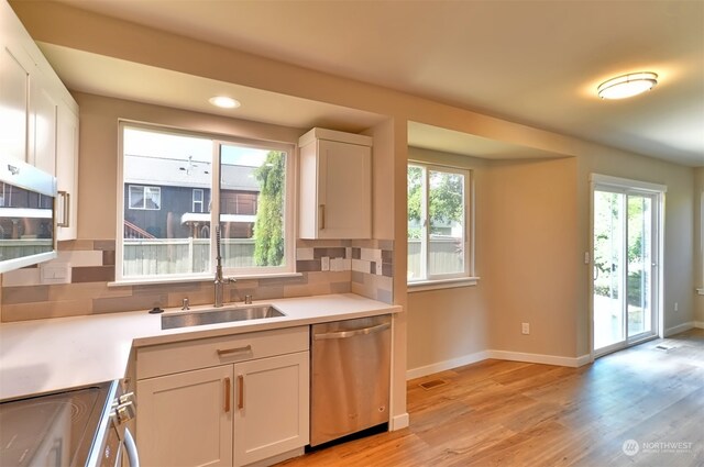 kitchen featuring sink, backsplash, dishwasher, and light hardwood / wood-style floors