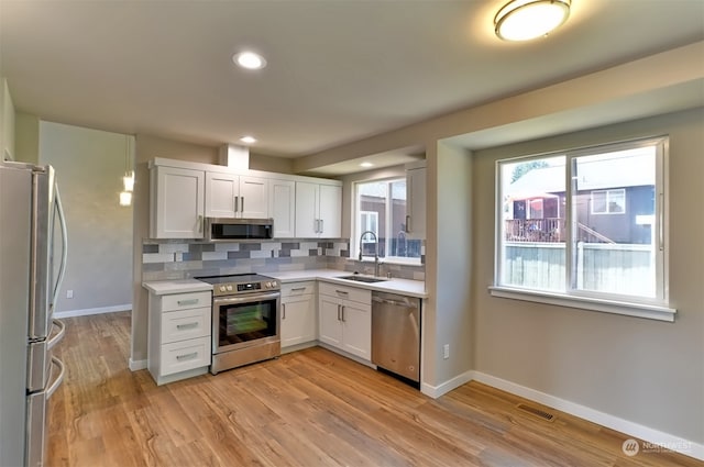 kitchen featuring sink, tasteful backsplash, stainless steel appliances, and white cabinetry