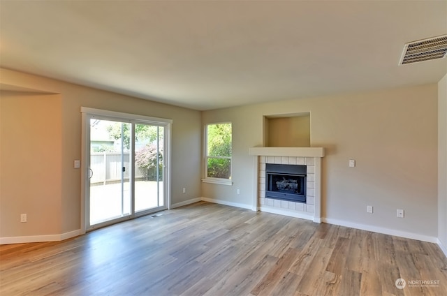 unfurnished living room with a tile fireplace and hardwood / wood-style floors