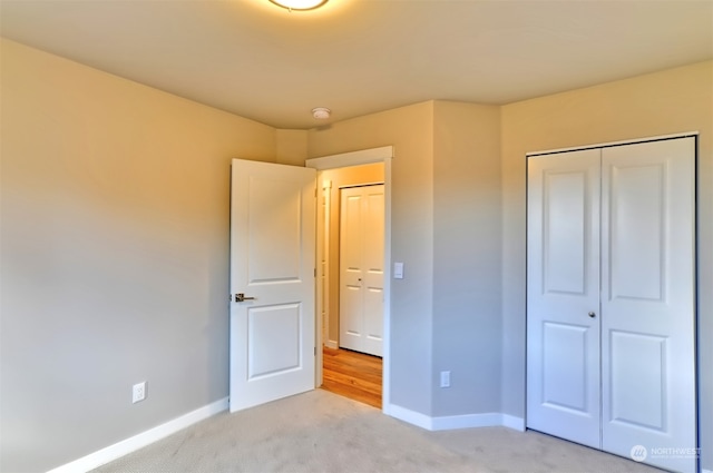 unfurnished bedroom with a closet and light colored carpet