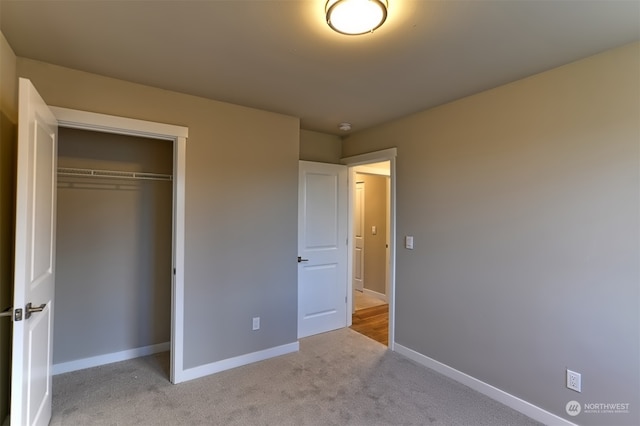 unfurnished bedroom with a closet and light colored carpet