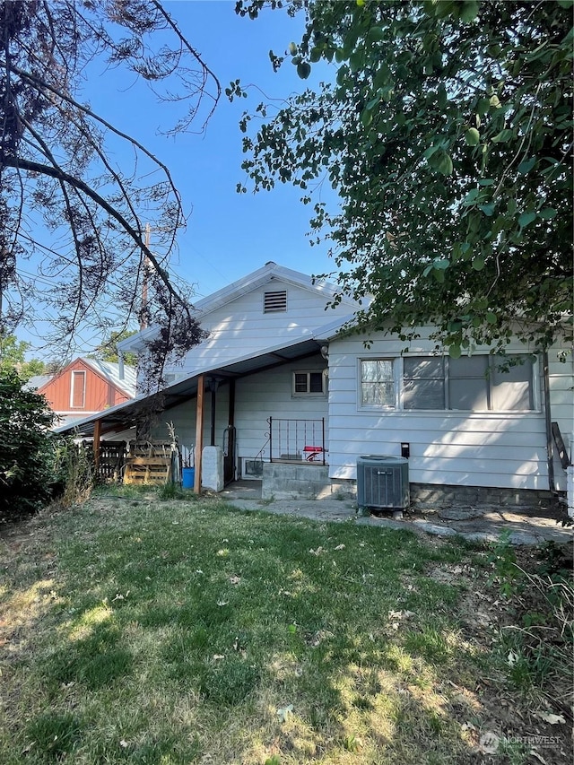 back of house featuring central AC and a yard