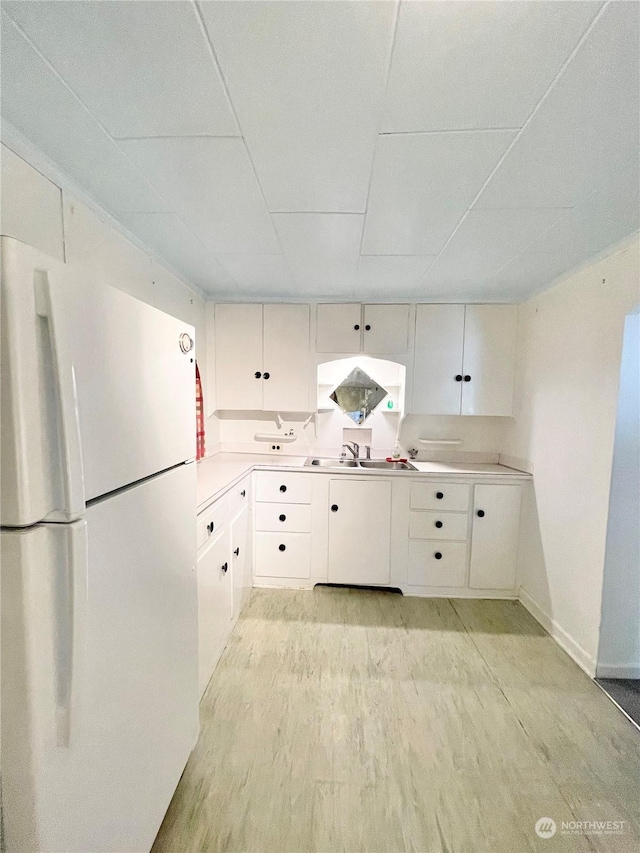 kitchen featuring sink, white cabinets, white refrigerator, light hardwood / wood-style floors, and a drop ceiling