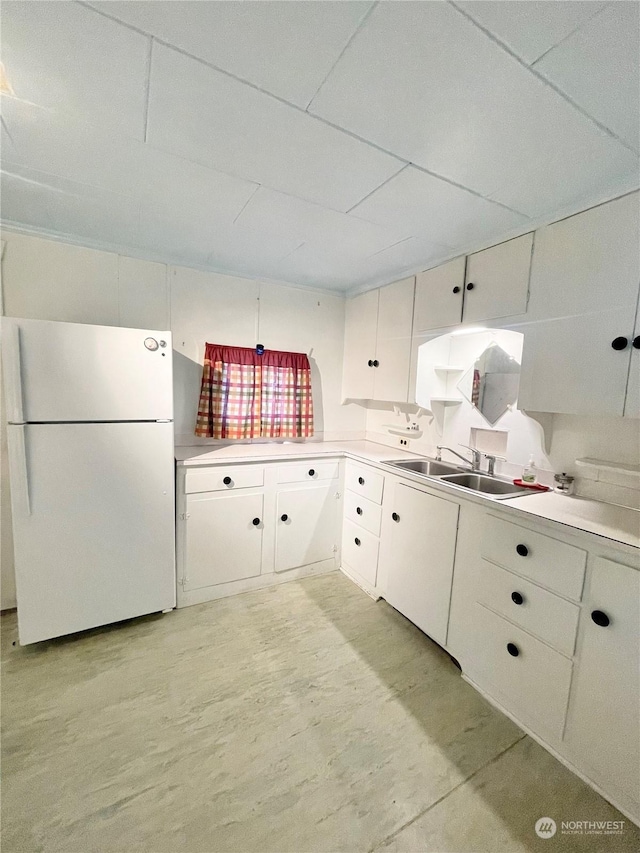 kitchen featuring white refrigerator, sink, and white cabinets