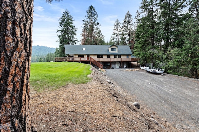 rustic home featuring stairs, dirt driveway, a front lawn, and a deck