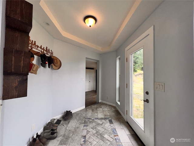 doorway to outside featuring a raised ceiling