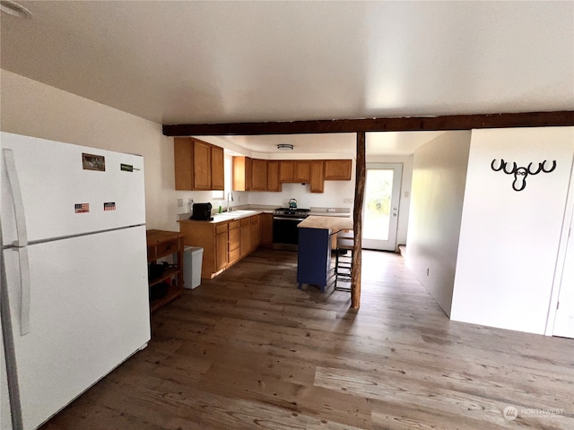 kitchen featuring a kitchen bar, beam ceiling, white refrigerator, stainless steel stove, and a kitchen island