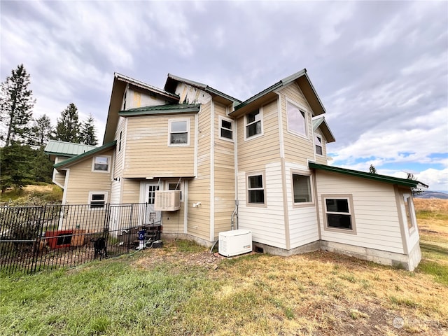 rear view of property with cooling unit and a lawn