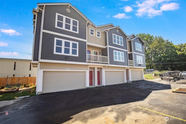 multi unit property featuring an attached garage, driveway, and fence