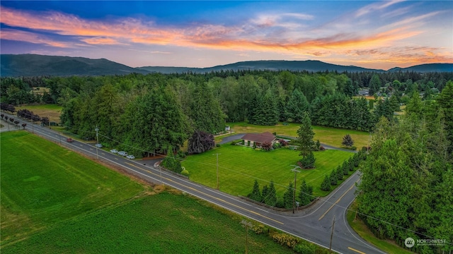 aerial view at dusk featuring a mountain view and a wooded view