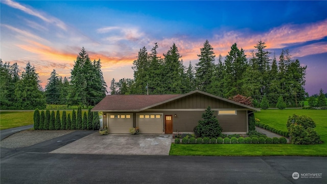 view of front facade featuring driveway, a yard, and an attached garage