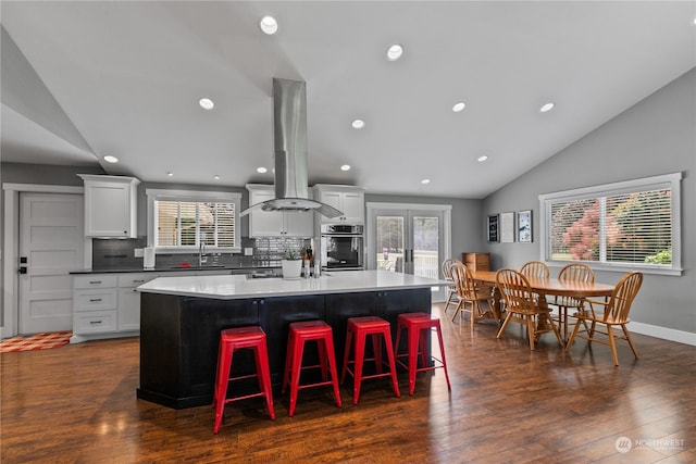 kitchen with stainless steel oven, a healthy amount of sunlight, vaulted ceiling, french doors, and a kitchen bar