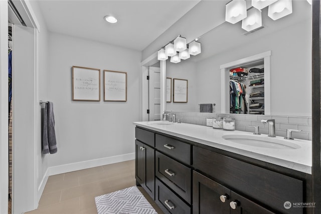 full bath with double vanity, tasteful backsplash, a sink, and baseboards