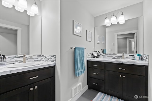 full bathroom with tasteful backsplash, visible vents, two vanities, and a sink