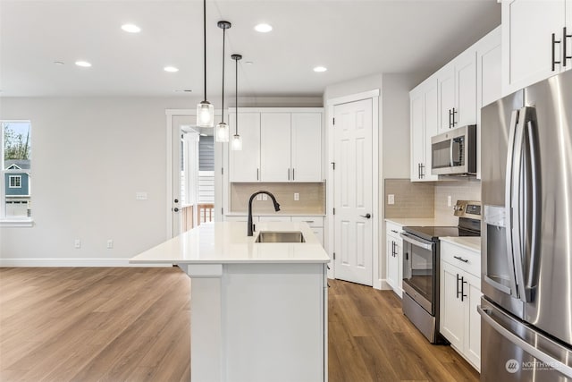 kitchen featuring sink, a kitchen island with sink, white cabinetry, hanging light fixtures, and stainless steel appliances