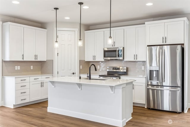 kitchen featuring hanging light fixtures, sink, white cabinets, and appliances with stainless steel finishes